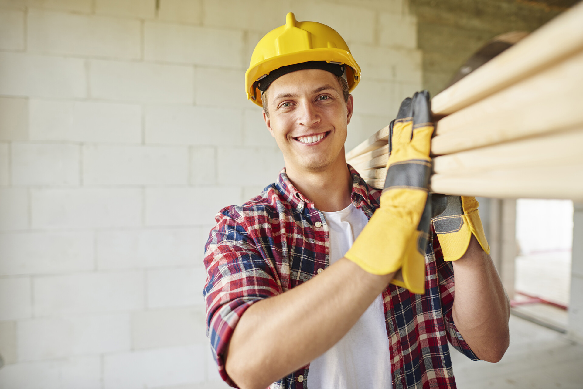 Younger carpenter holds wooden planks